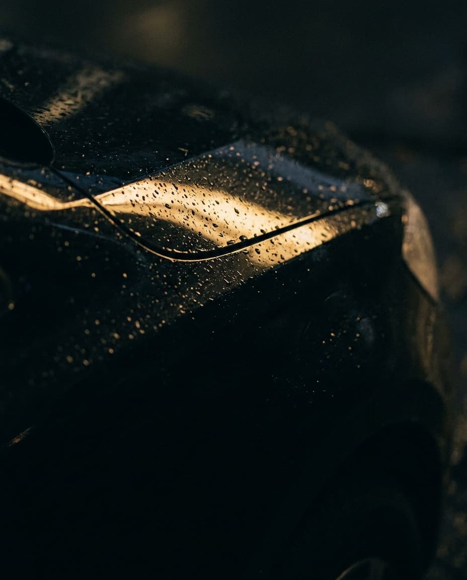Nasse Karosserie eines VW Touran bei Nacht mit goldenem Lichtreflex